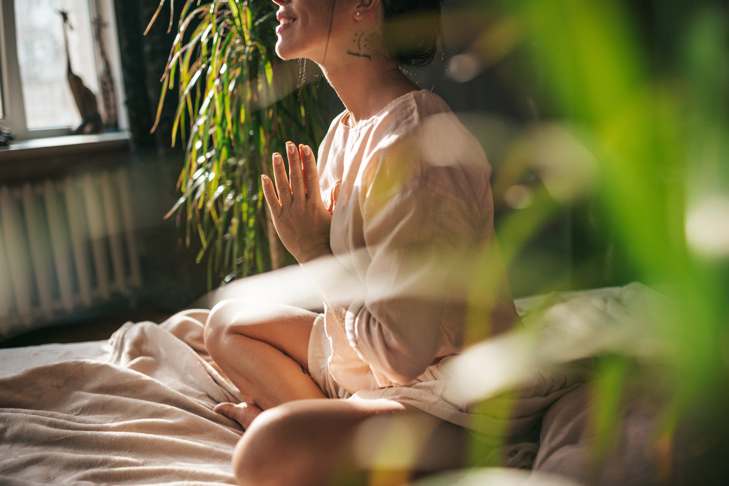 Person meditating with hands clasped in a serene indoor setting